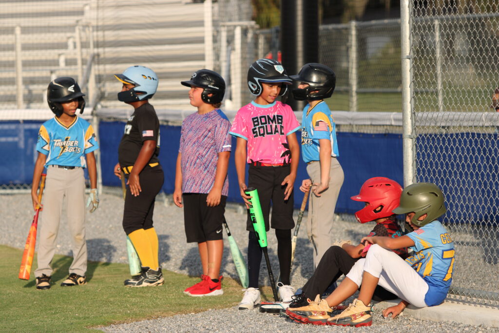 Camp youngsters stand in line waiting for their turn to bat at the plate.