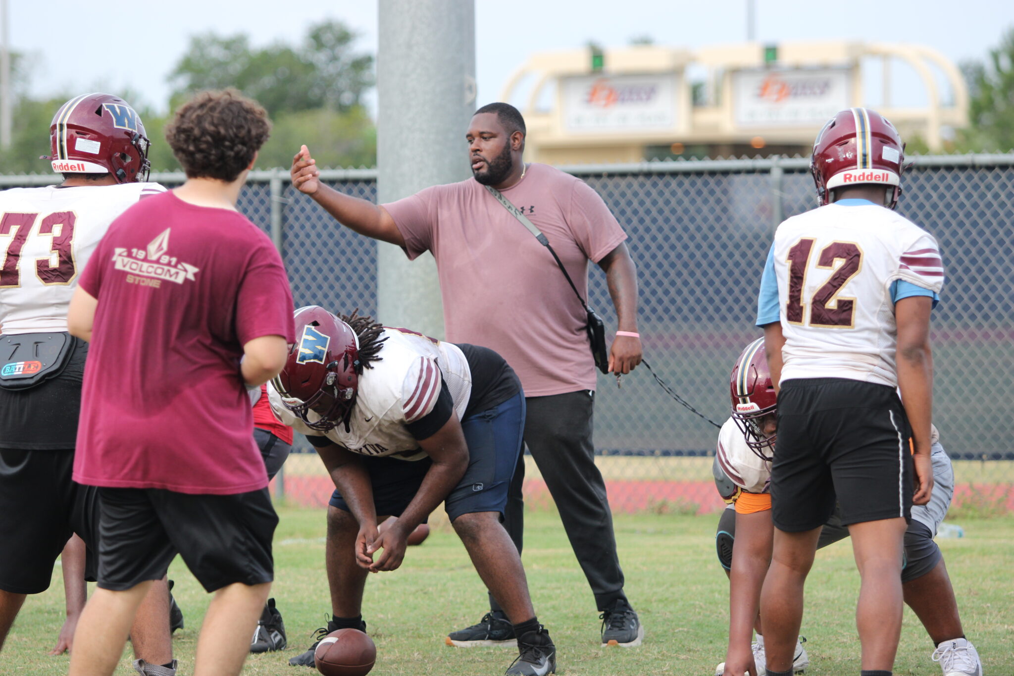 Coach Ashton Watts instructing the offense on pre-snap adjustments.