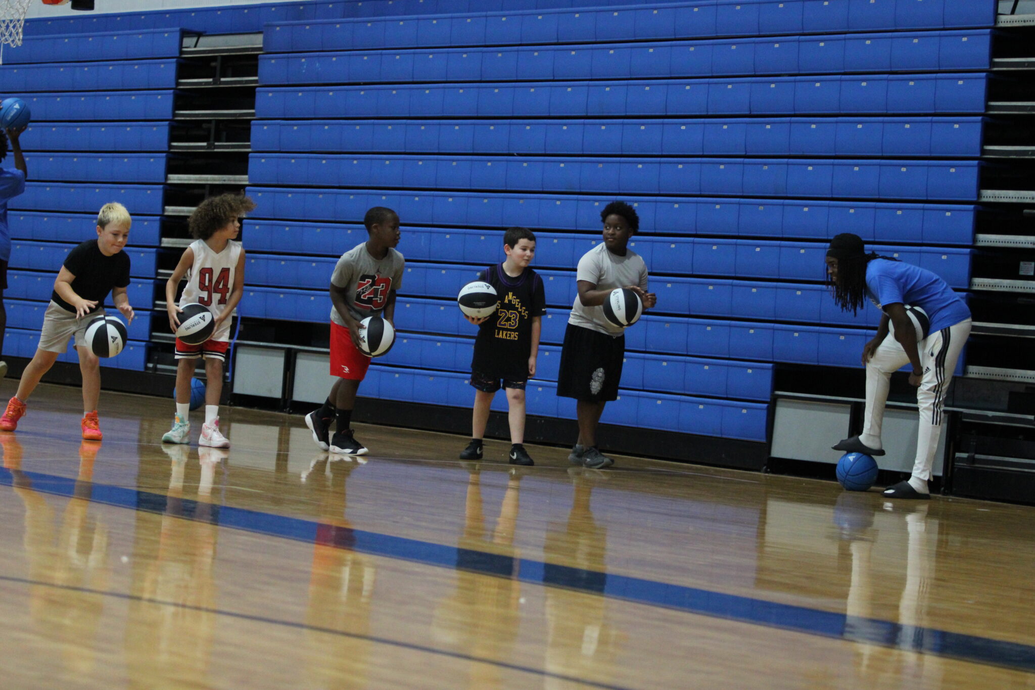 Jacques Evariste instructs young campers in a dribbling drill.