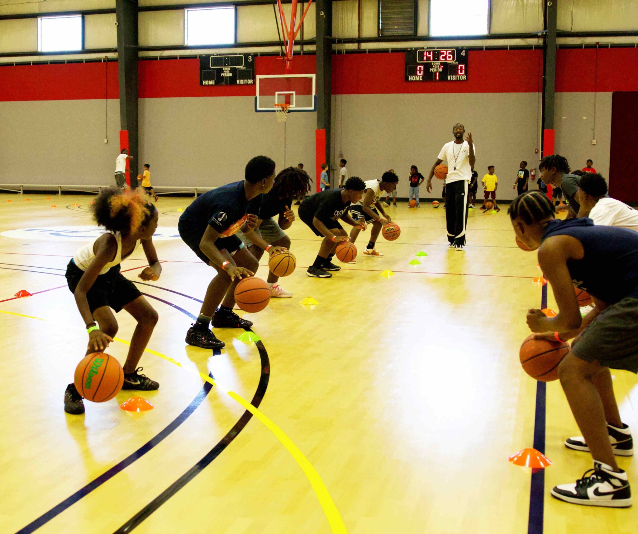 Jonathan Thompson training the clinic attendees in a dribbling drill, dribbling the ball with their heads up in Time to Trains youth basketball clinic at The Well Activity Center in Apopka.