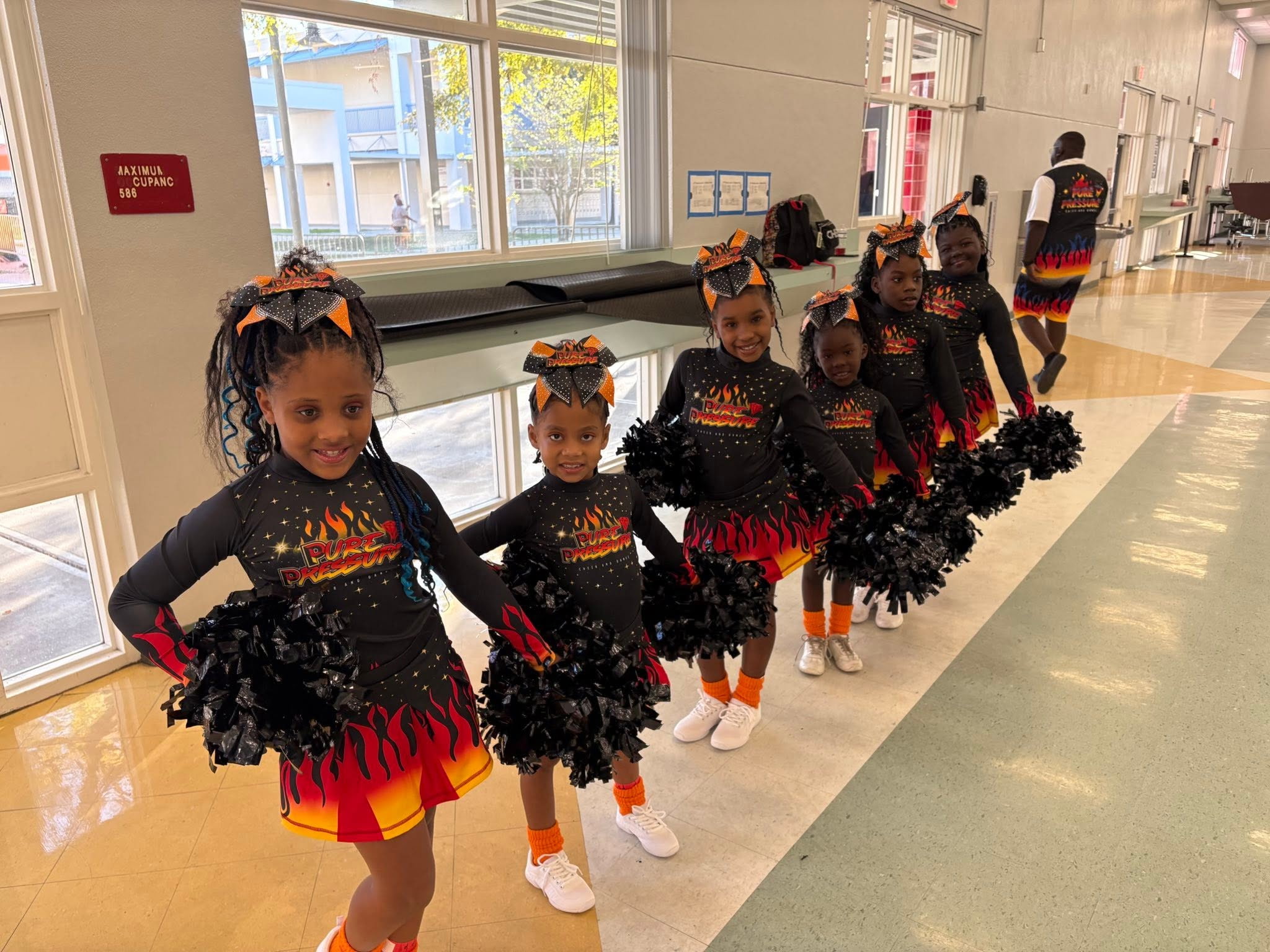 Pure Pressure Cheer and Dance girls lineup and pose for a photo in a studio.