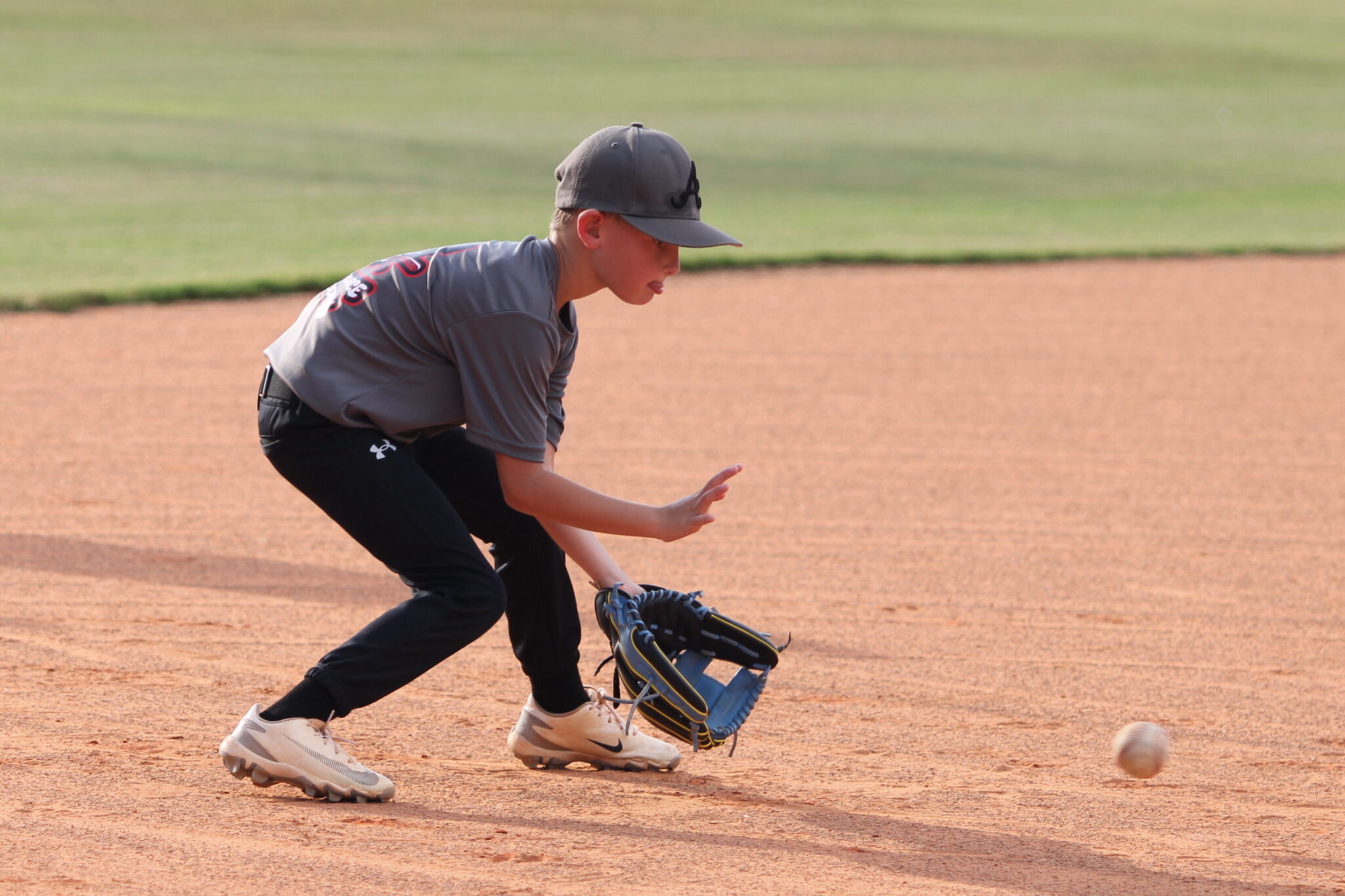 Young athlete at the Apopka High School Youth Baseball Camp fielding a ground ball hit by Coach Scott Garland
