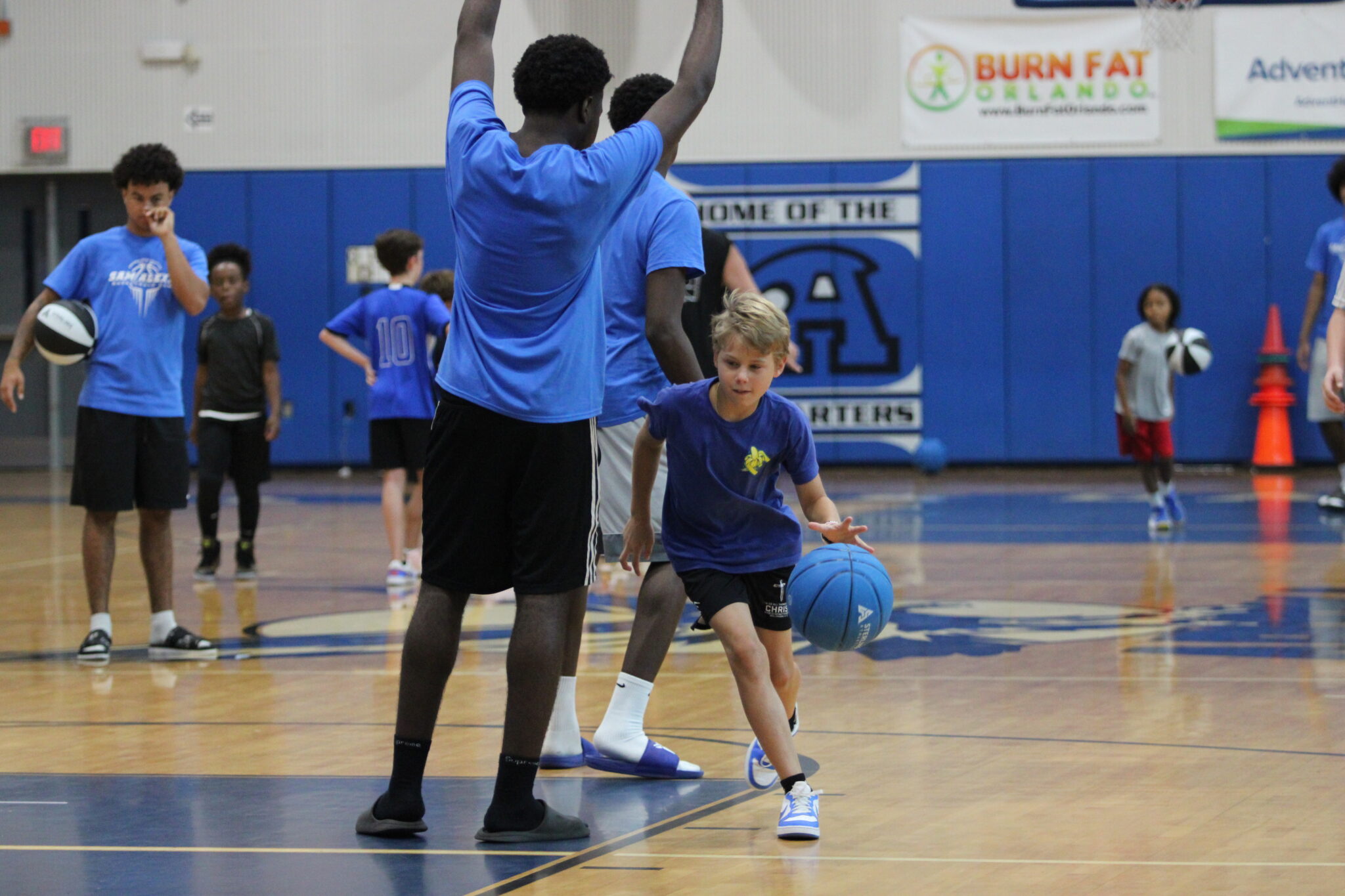 Young camper dribbles around a current Blue Darter and drives to the hoop.