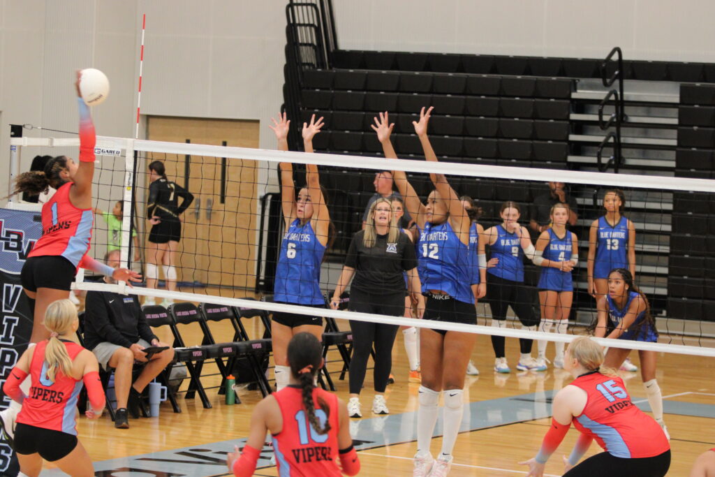 Isabel Romero and Laila White jump up at the net in attempt to block the incoming LBV spike.