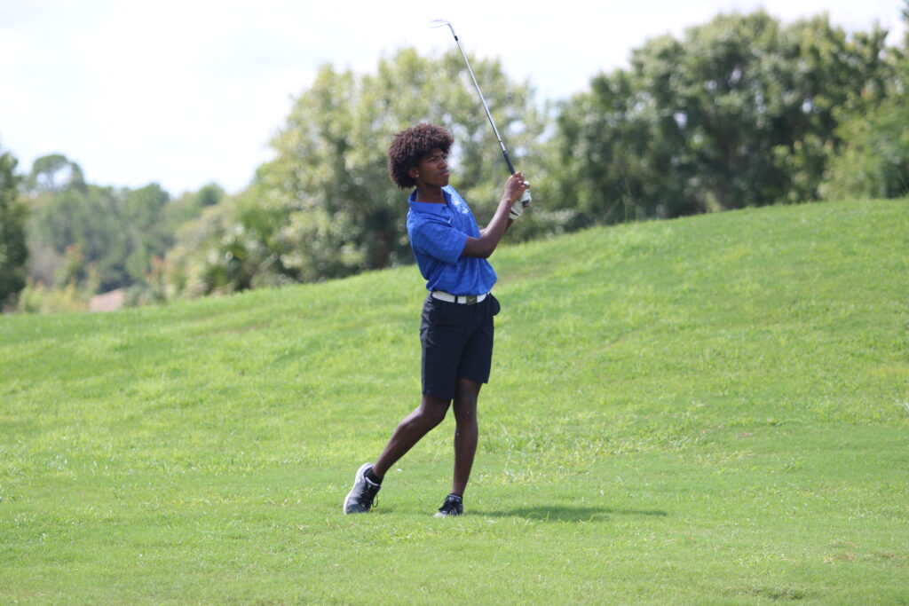 Senior Isaiah Smith hits a ball from the rough onto the green.