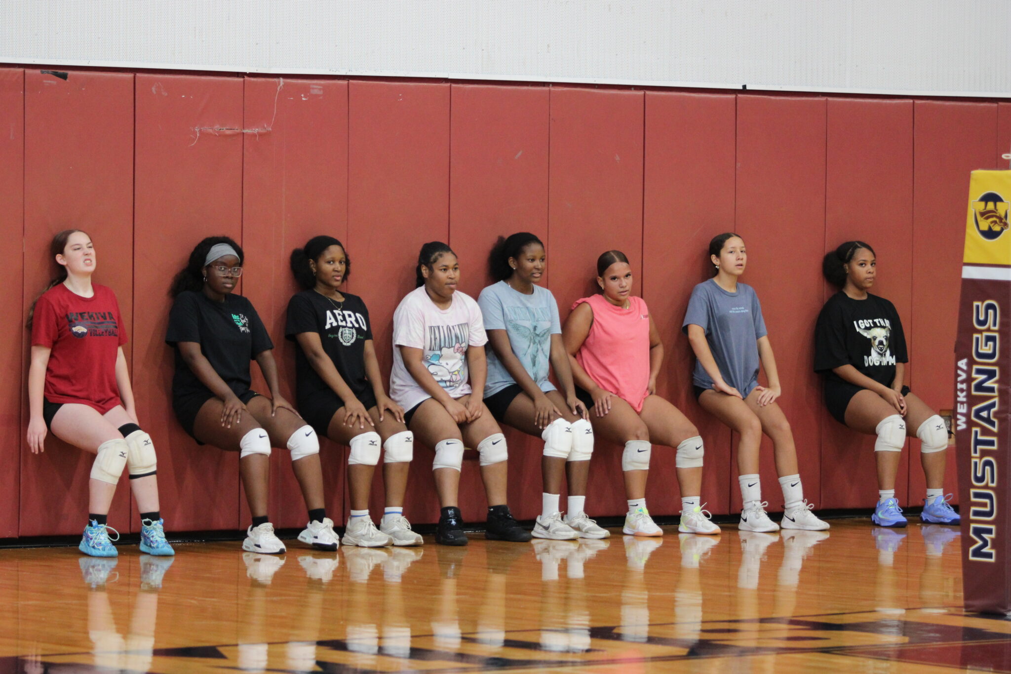 Junior Varsity girls do wall sits as a part of Orlando Fire Dept. firefighter Ely Sanchez's team workout.