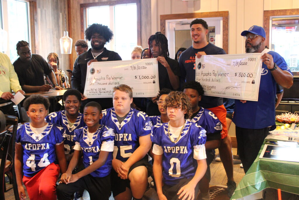 Kevin Roberts (L) and Kingston Shaw (R) present checks to give back to Apopka Pop Warner.
