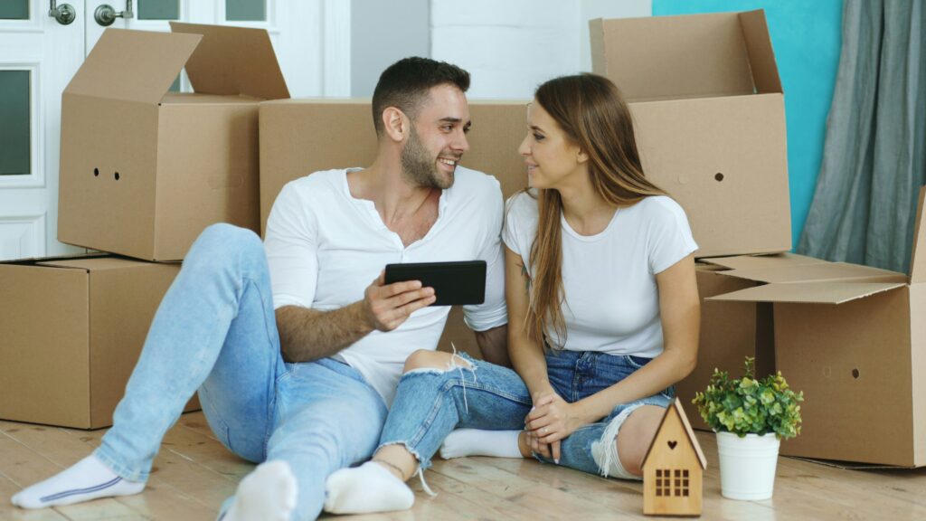 Couple sitting on floor surrounded by moving boxes in a new home