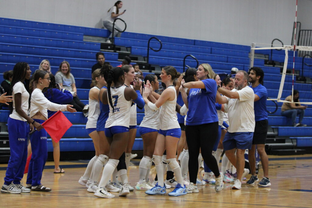 Blue Darter players and coaches group up and go down the high five line after their sweep of Evans.