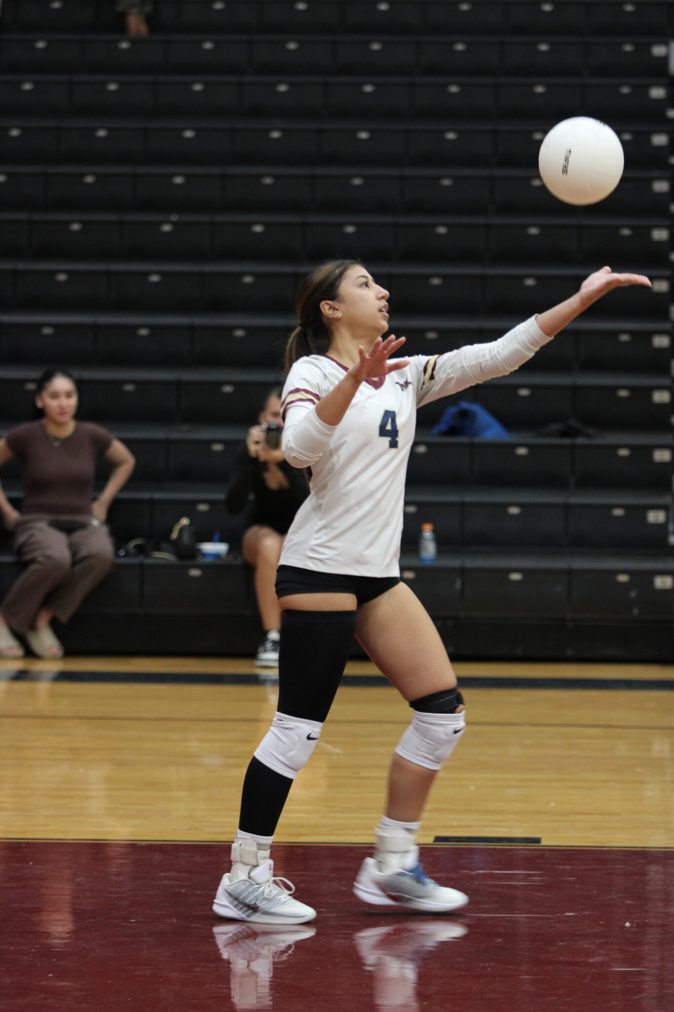 Elyanna Sanchez tosses up a ball to serve.