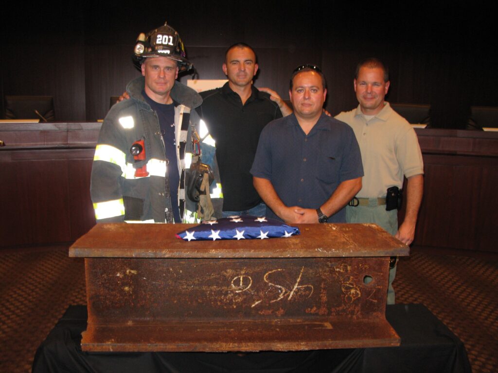 Former FDNY firefighter Jimmy Brown, left, stands with then-Winter Garden Fire Battalion Chief Brian Sanders, then-Belle Isle police Officer Tren Trendafilov and then-Winter Garden police Detective James Cox behind a section of steel recovered from the World Trade Center. The four traveled to New York in 2011 to retrieve the beam for Winter Garden, where it later became part of the city's 9/11 memorial.