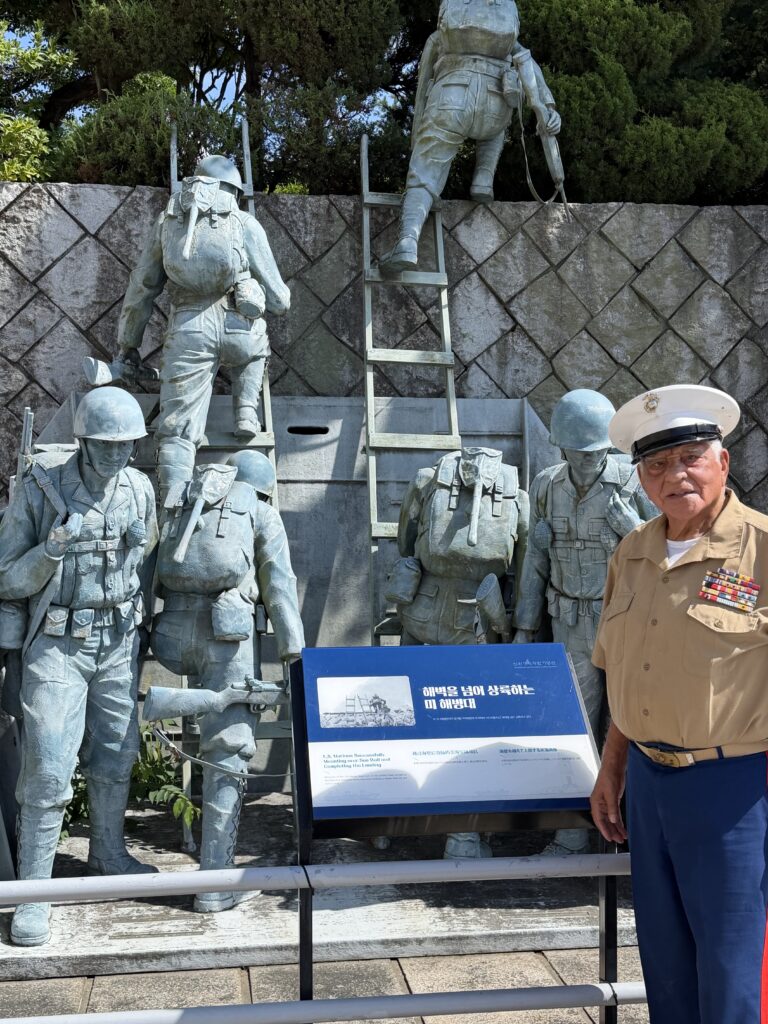 Lou Boria stands with the statue of the beach landing he executed in Incheon.