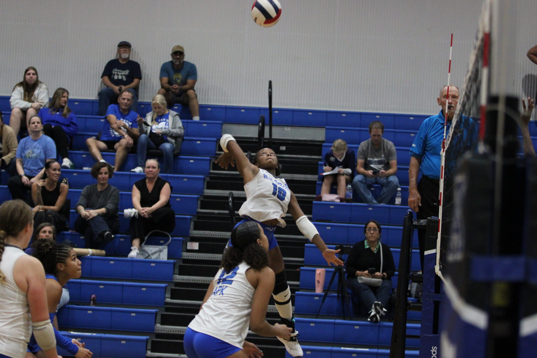 Marie Hughes leaps up at the left side of the net to spike down a ball set by Kalissa Burske.