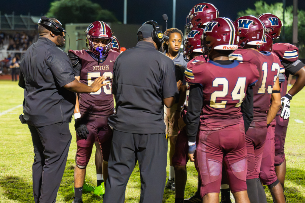 Coach Ashton Watts and Jerry Middleton huddle with the defense during a timeout.