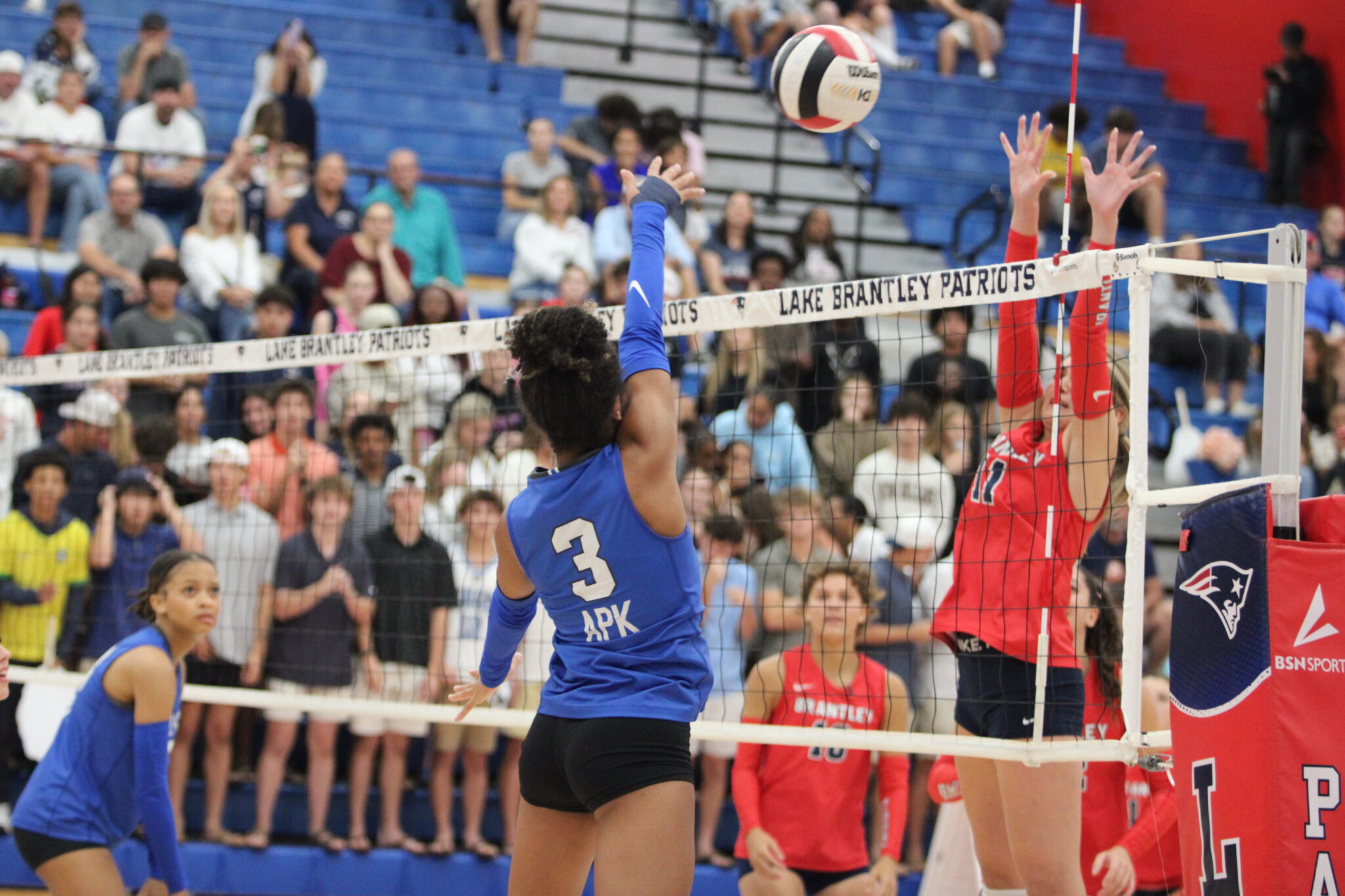 Kiana Napier hits a ball past the blocking hands of a Patriot.