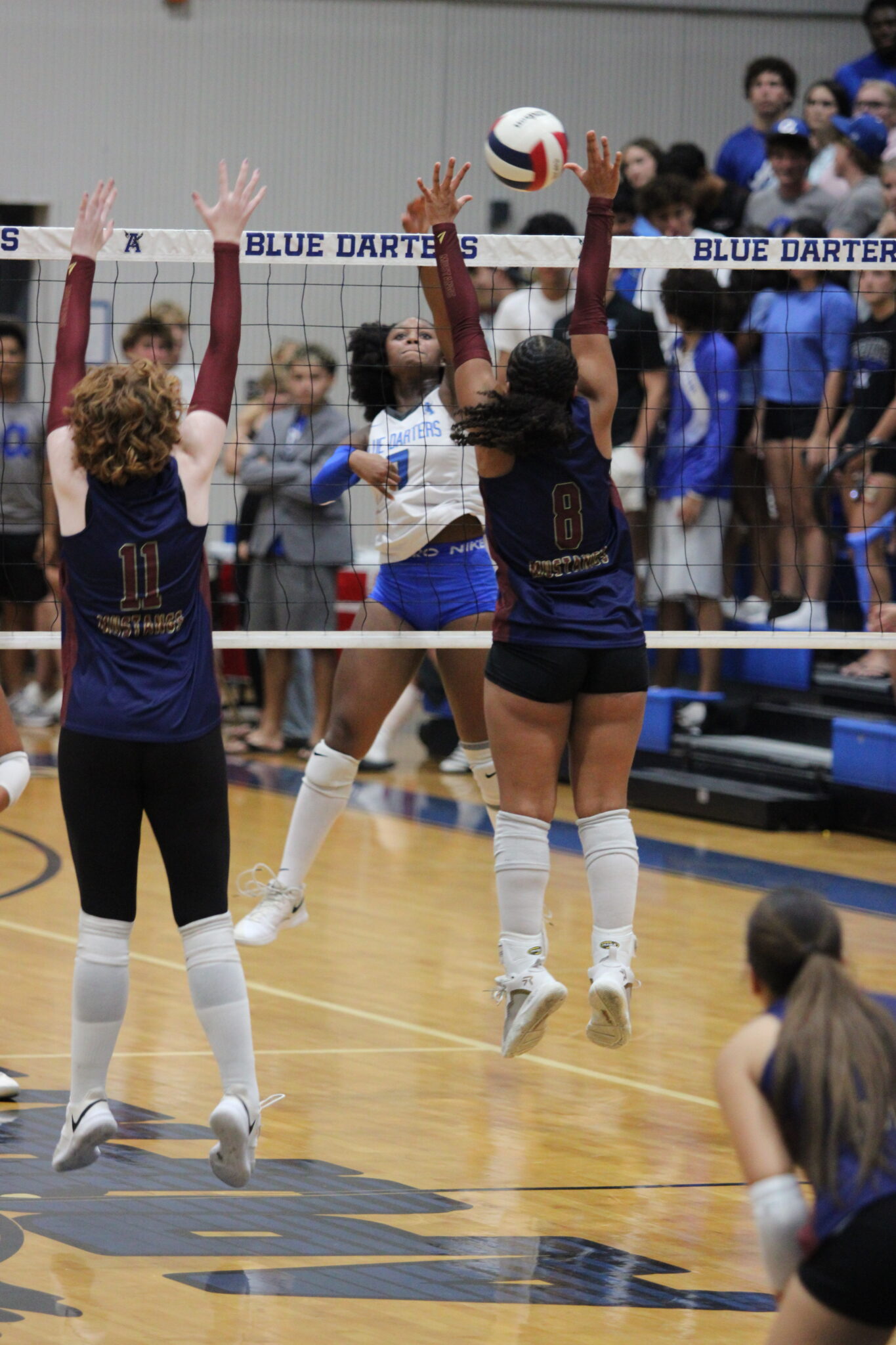 Senior Lillian Phillips spikes a ball past the hands of seniors Leona Salasek and Isabella Espada.